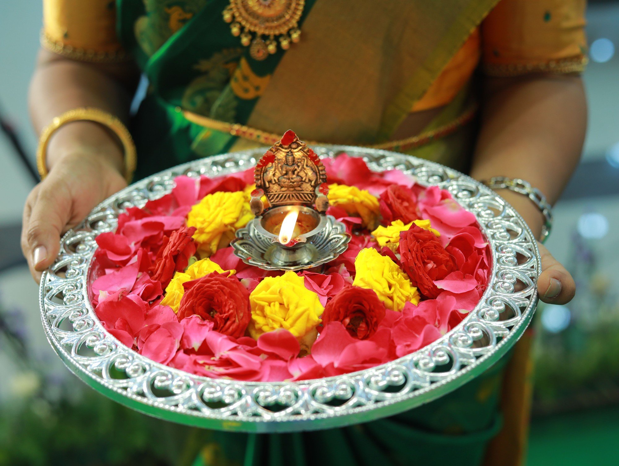 A family holds a flower-filled puja offering plate